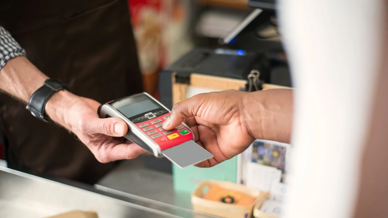 Un client paie par carte sur un terminal tendu par-dessus le comptoir